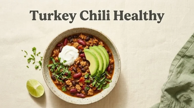 Overhead view of turkey chili in a bowl topped with yogurt and avocado, with the title Turkey Chili Healthy displayed above on a linen background.
